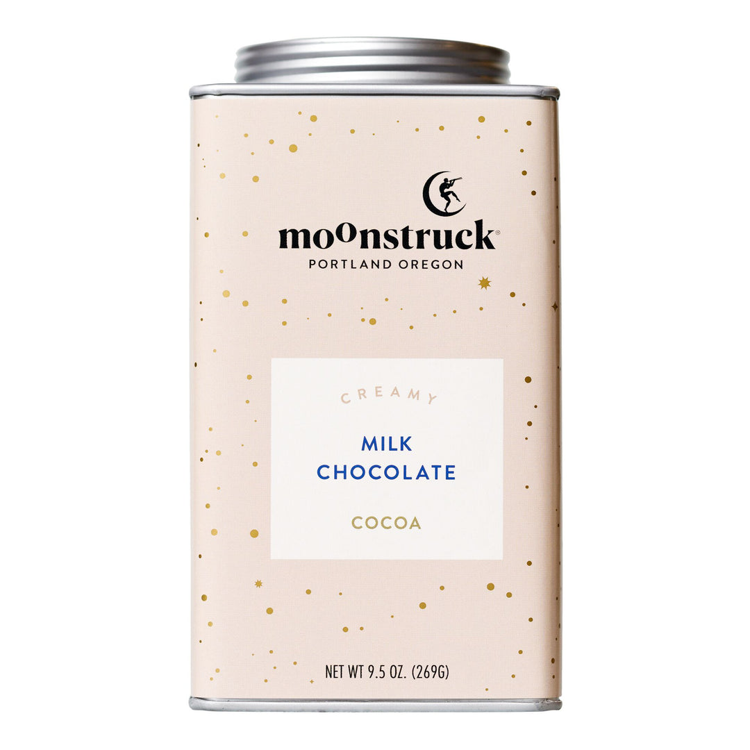 A container of Moonstruck Creamy Milk Chocolate Cocoa with a light-colored label and speckled pattern.