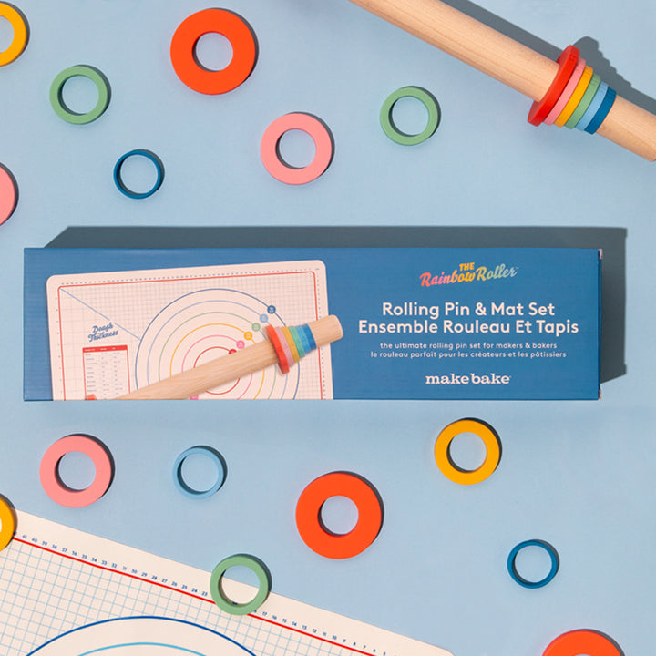 Make Bake Brand Rainbow Roller 19" Straight Maplewood Rolling Pin with Depth Rings and Silicone Baking Mat shown on a blue background.