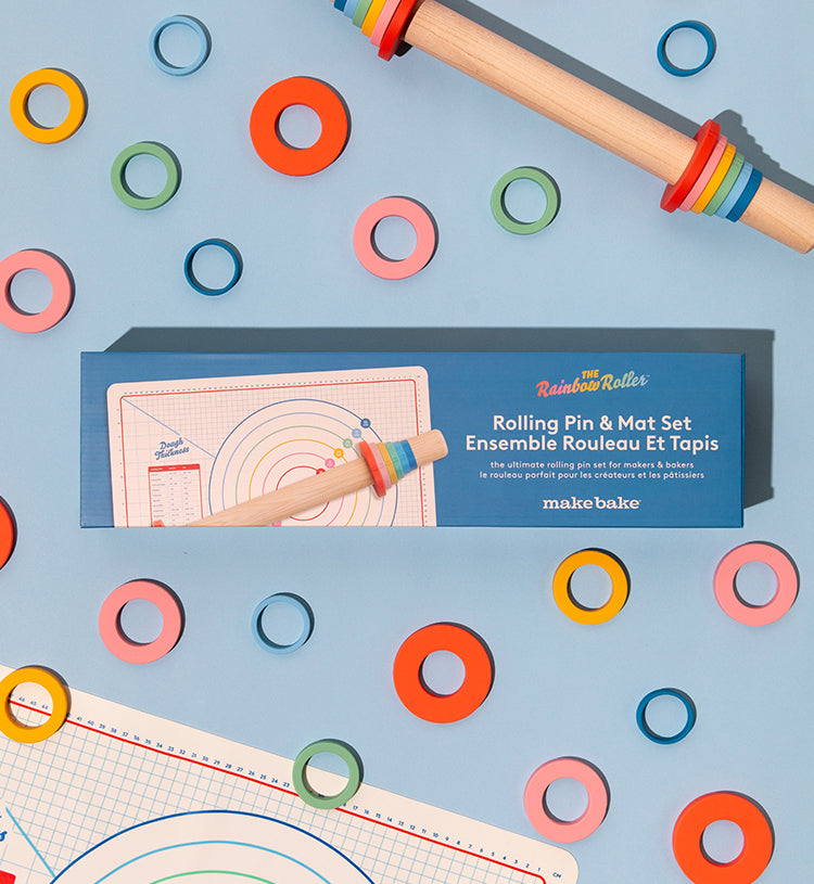 Make Bake Brand Rainbow Roller 19" Straight Maplewood Rolling Pin with Depth Rings and Silicone Baking Mat shown on a blue background.