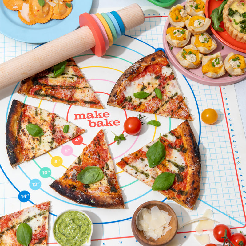 Slices of pizza on a baking sheet with ingredients and a rolling pin.