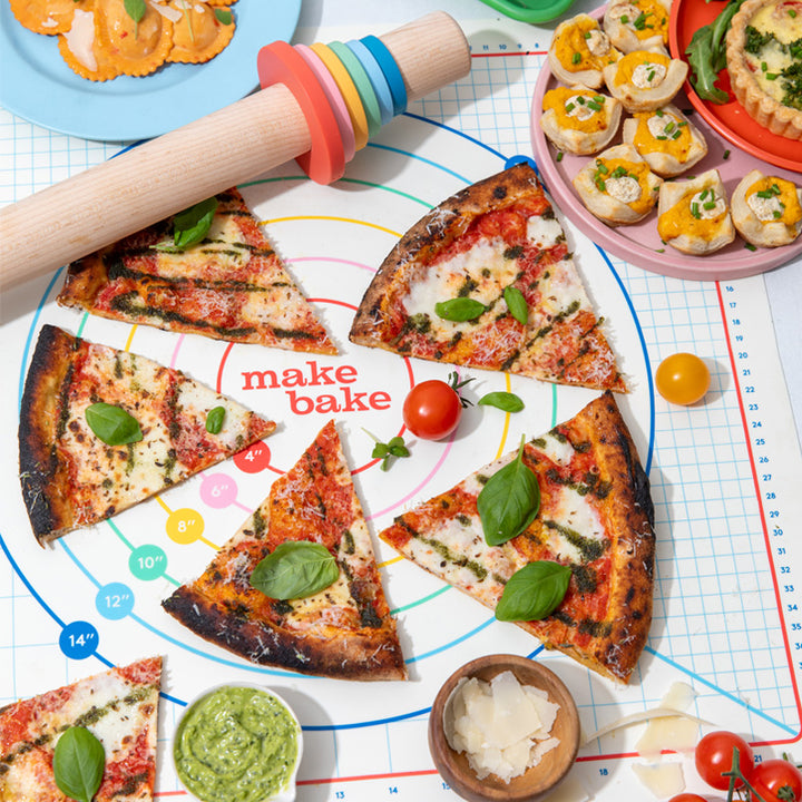 Slices of pizza on a baking sheet with ingredients and a rolling pin.