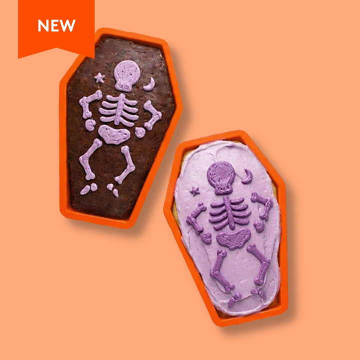 Two Halloween-themed cupcakes in the shape of coffins with skeleton designs on an orange background.
