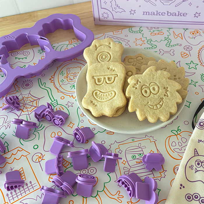 Monster themed sugar cookies created using Stamp & Bake cookie stamps and cookie cutter set displayed on a kitchen counter until a Halloween themed table runner.
