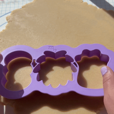 Video close up of someone using Make Bake's Lots Of Monsters cookie cutter to cut sugar cookie dough.