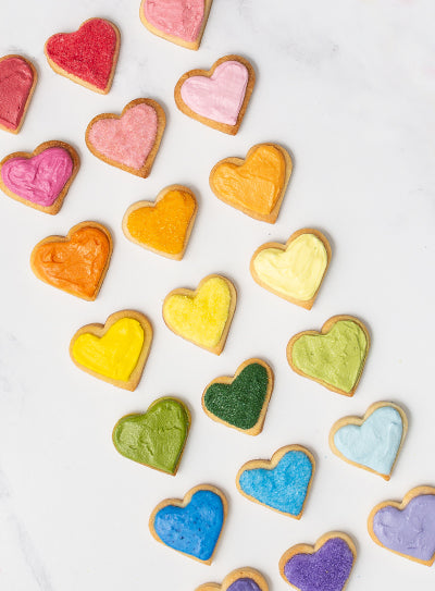 Naturally colored heart-shaped cookies in rainbow colors arranged on a white background