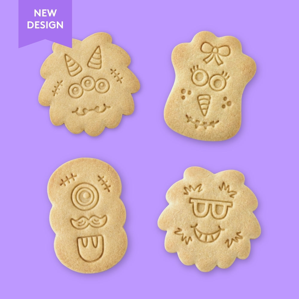 Four monster face-shaped cookies with stamped designs on a red background, labeled 'New Design'.