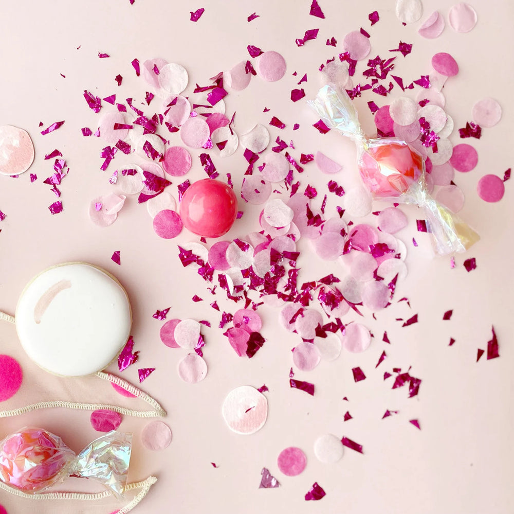 Pink and white candies with confetti on a pink background