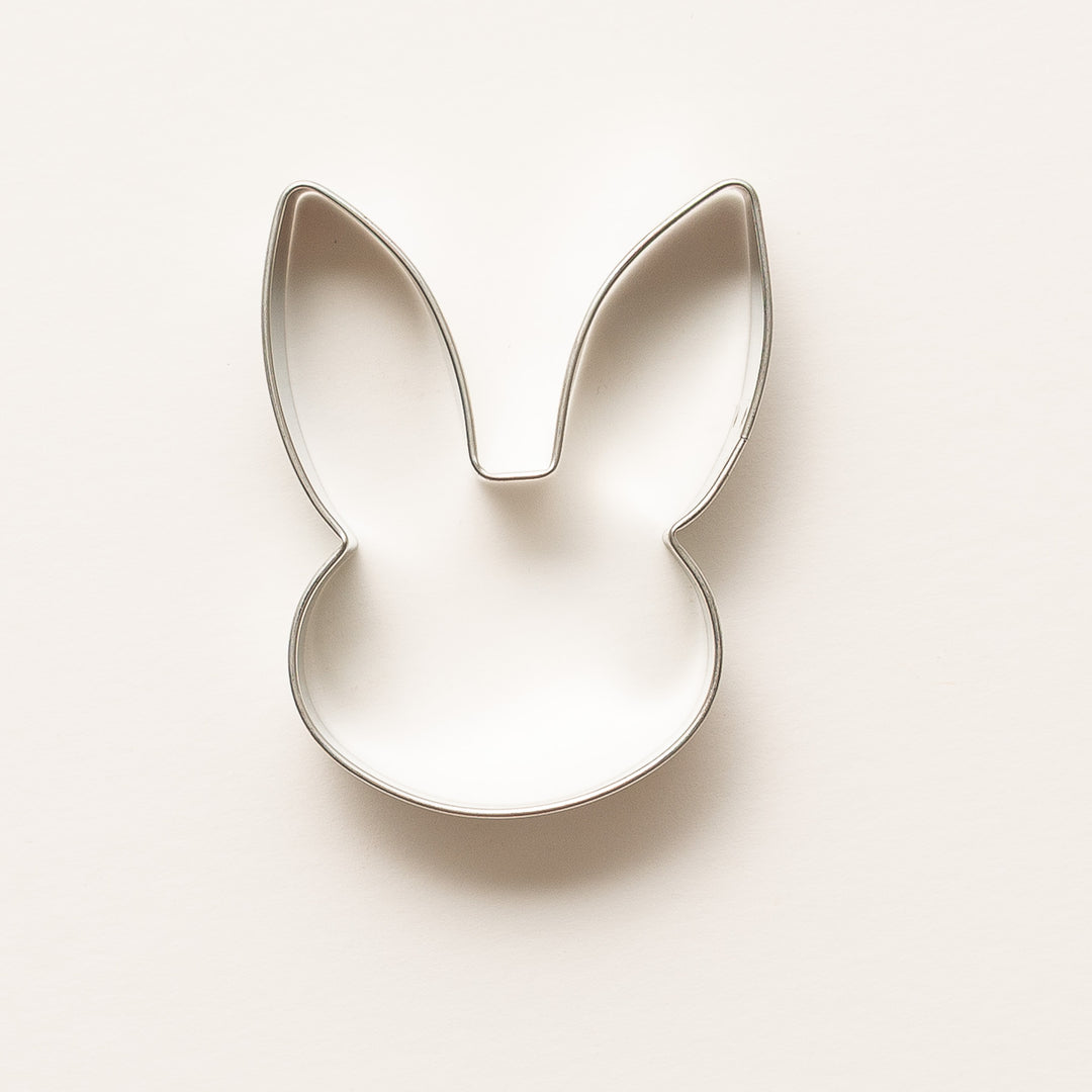Metallic bunny-shaped cookie cutter on a light beige background