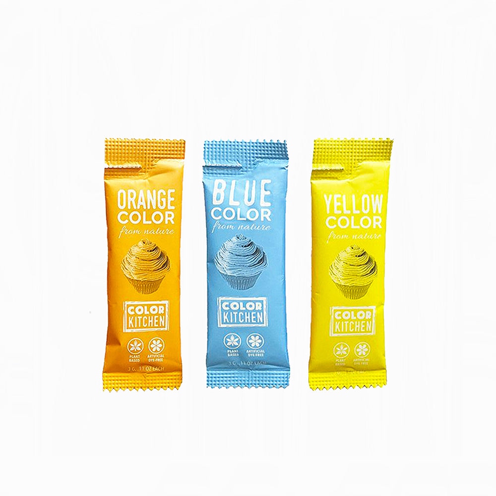 Three dye free food color packets from Color Kitchen in orange, blue, and yellow on a white background