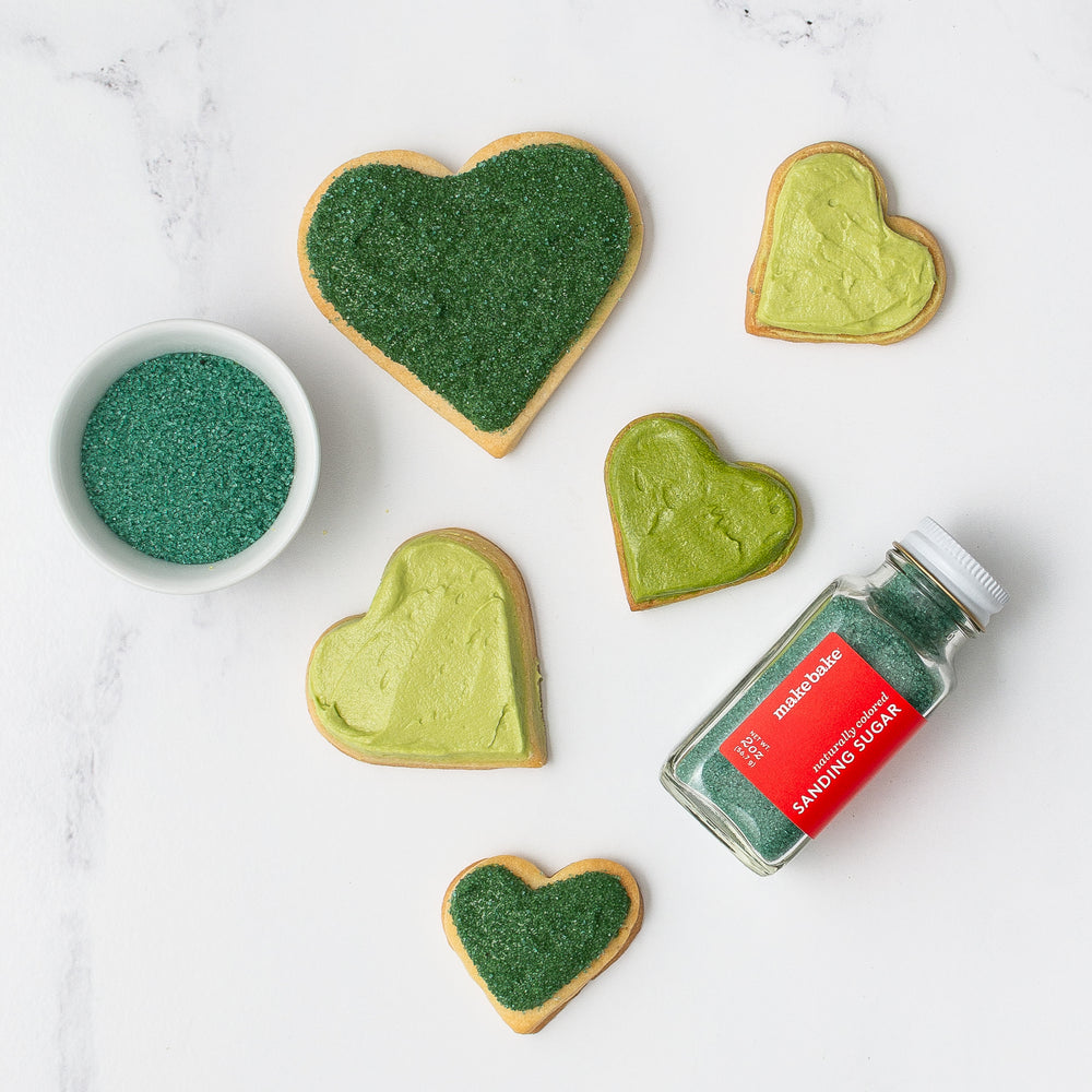 Heart shaped cookies decorated with dye-free green food colors and natural green sanding sugar on a white background