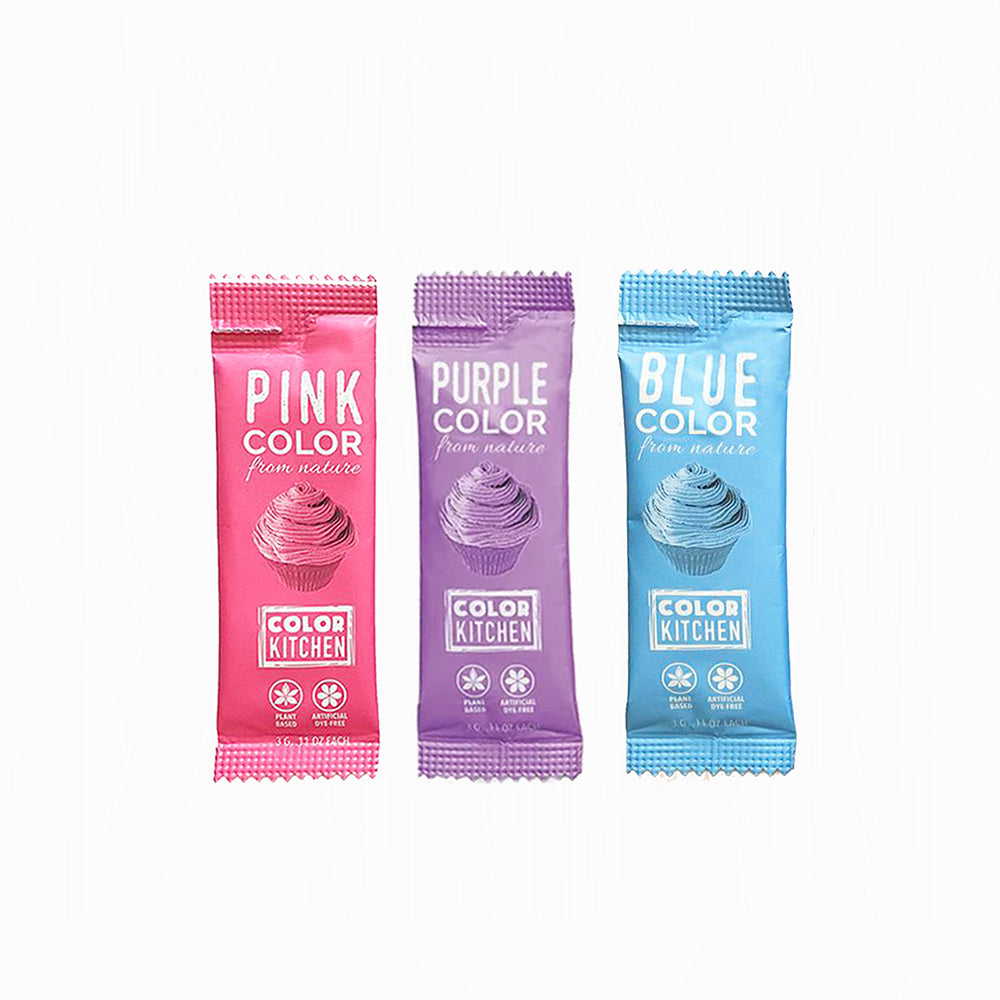 Three packets of Color Kitchen food colorings in pink, purple, and blue on a white background.
