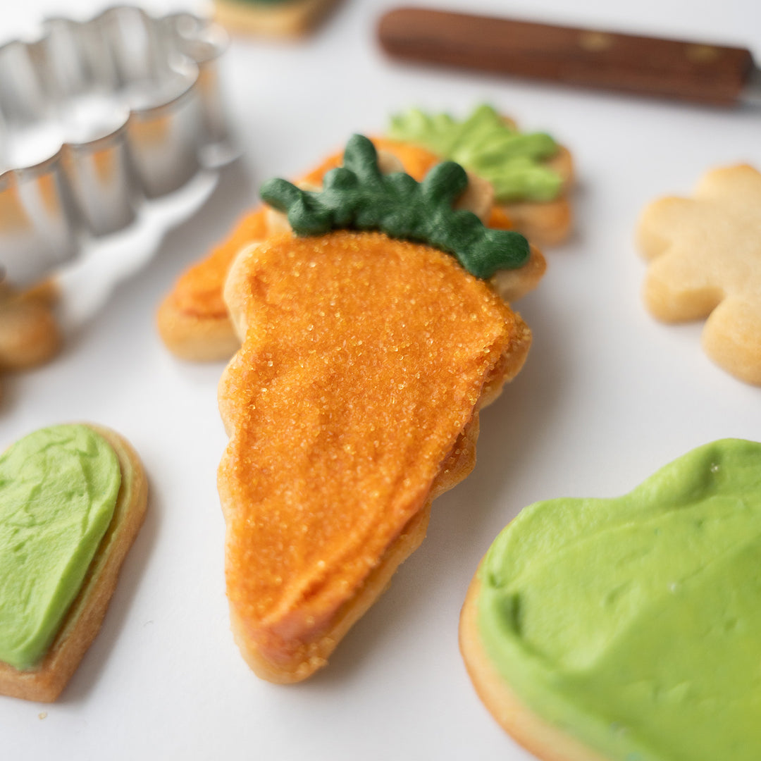 close up of a carrot sugar cookie decorated with dye-free sanding sugars and natural green food colors