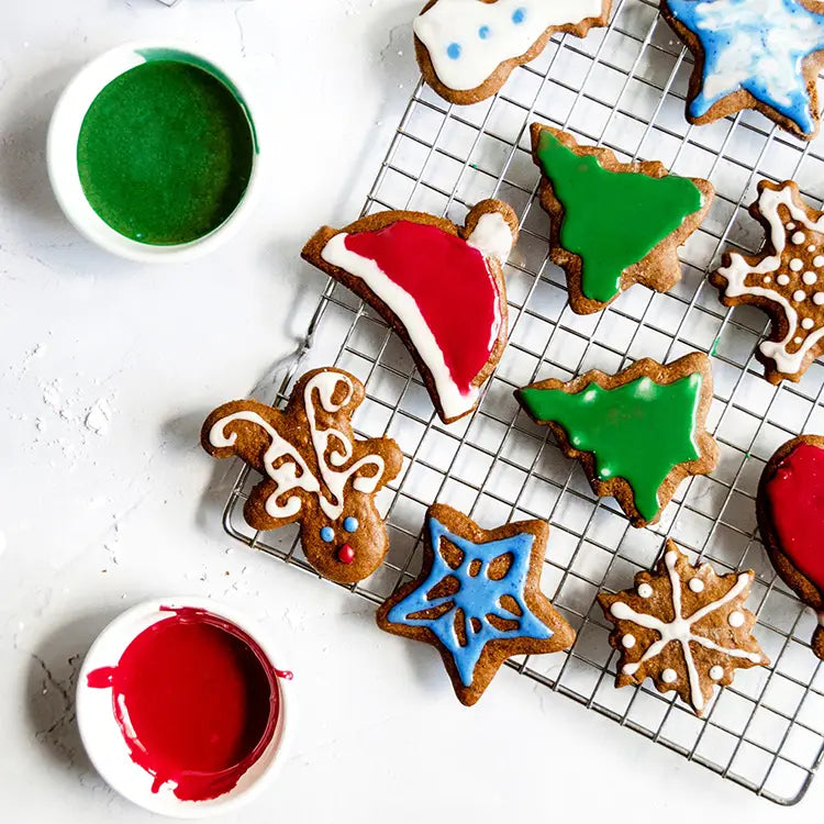 Variety of homemade gingerbread cookies  decorated with natural food colored icing on a cooling rack.