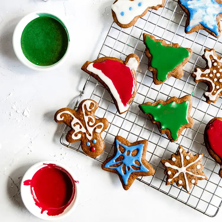 Variety of homemade gingerbread cookies  decorated with natural food colored icing on a cooling rack.