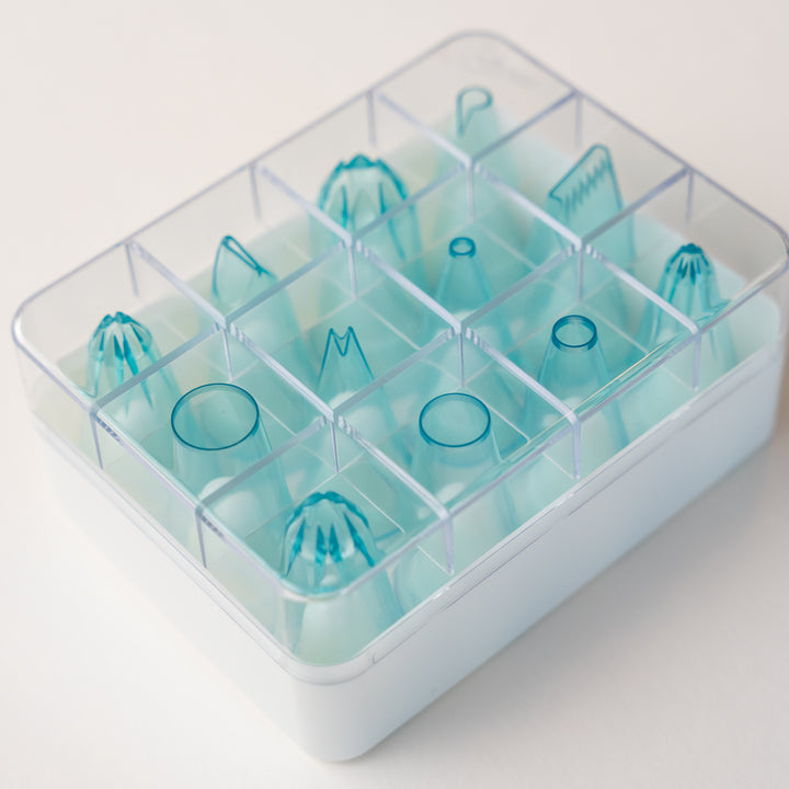 12 pieces clear blue piping tip set in various shapes for cake decorating shown in included plastic storage box.