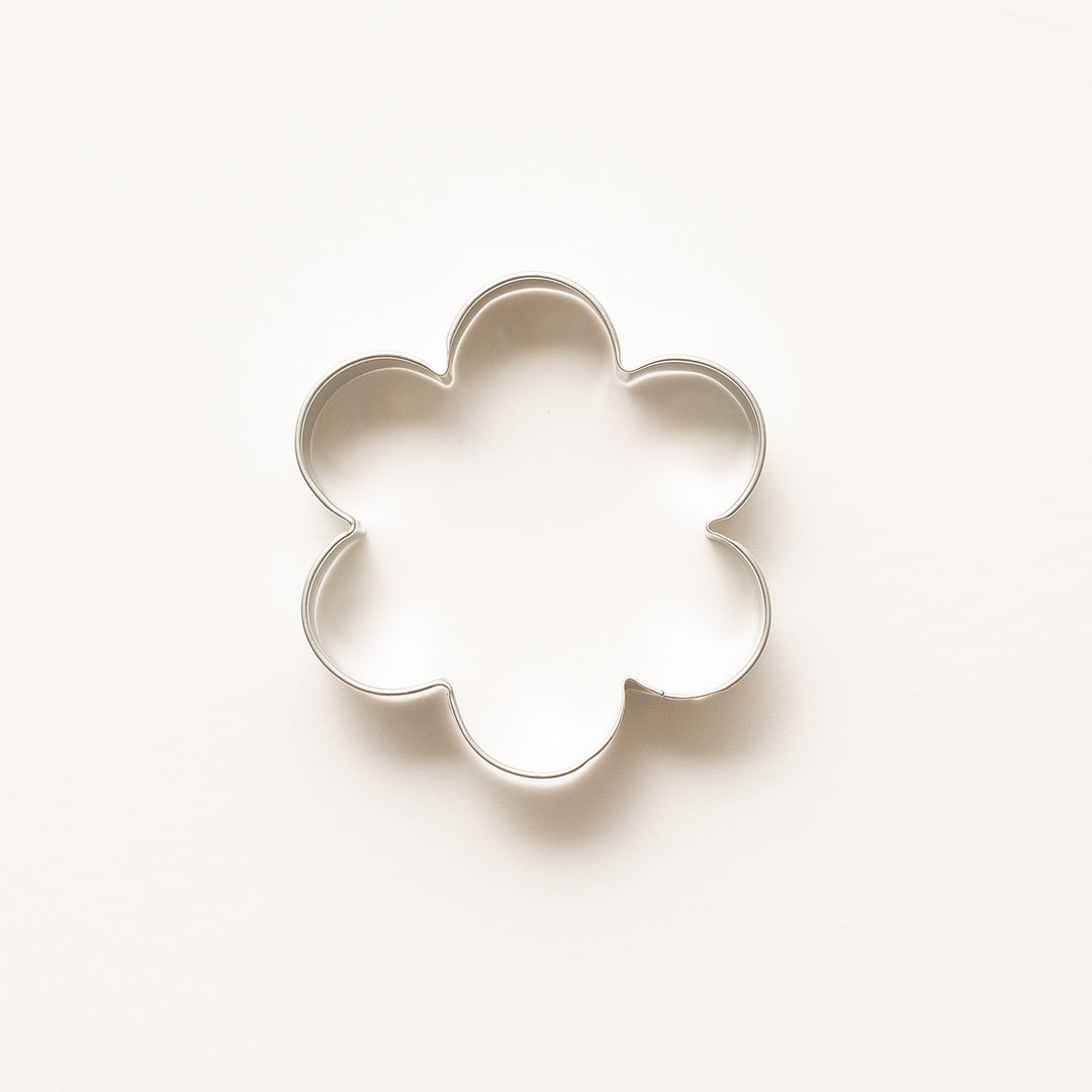 Flower-shaped cookie cutter on a light beige background