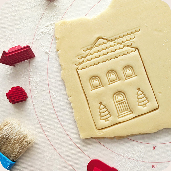 Cookie dough with a house-shaped cutter on a white surface