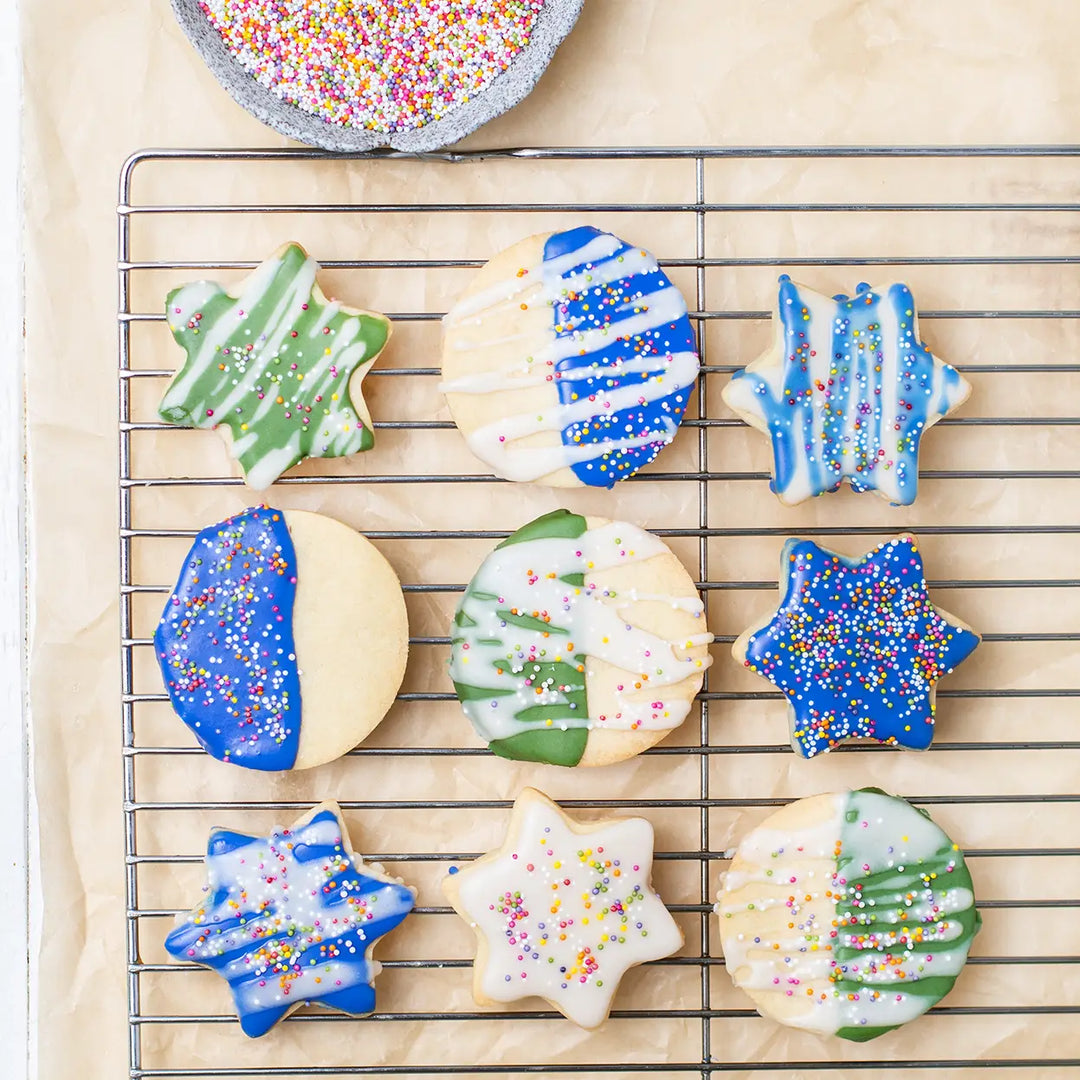homemade cookies decorated with dye free blue and green icing and topped with rainbow nonpareil sprinkles