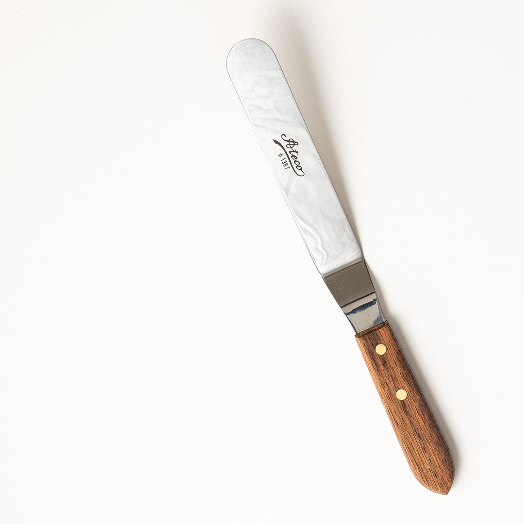 large spatula with wooden handle and metal blade on a white background