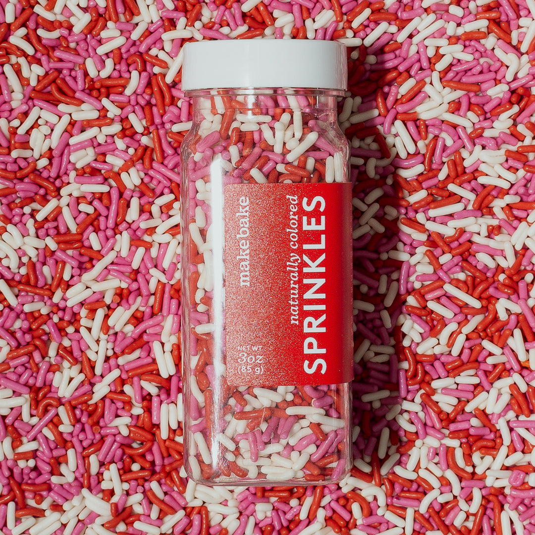Bottle of Make Bake Valentine's Sprinkle Mix with sprinkles in pink, red and white.
