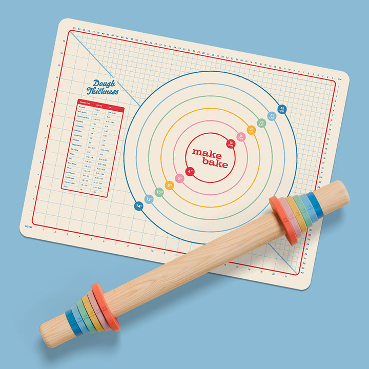 Baking mat with circular design and wooden rolling pin with rainbow guide rings on a blue background