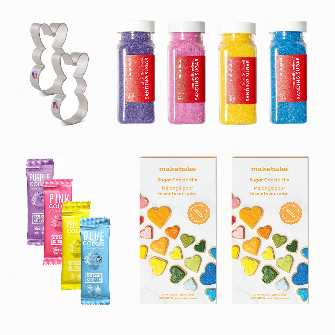 Bunny themed cookie kit includes colorful dye-free sanding sugar and natural food color packets in purple, pink, yellow and blue, cookie mix boxes and a bunny cookie cutter on a white background