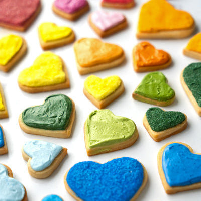 Colorful dye-free rainbow heart-shaped cookies on a white surface