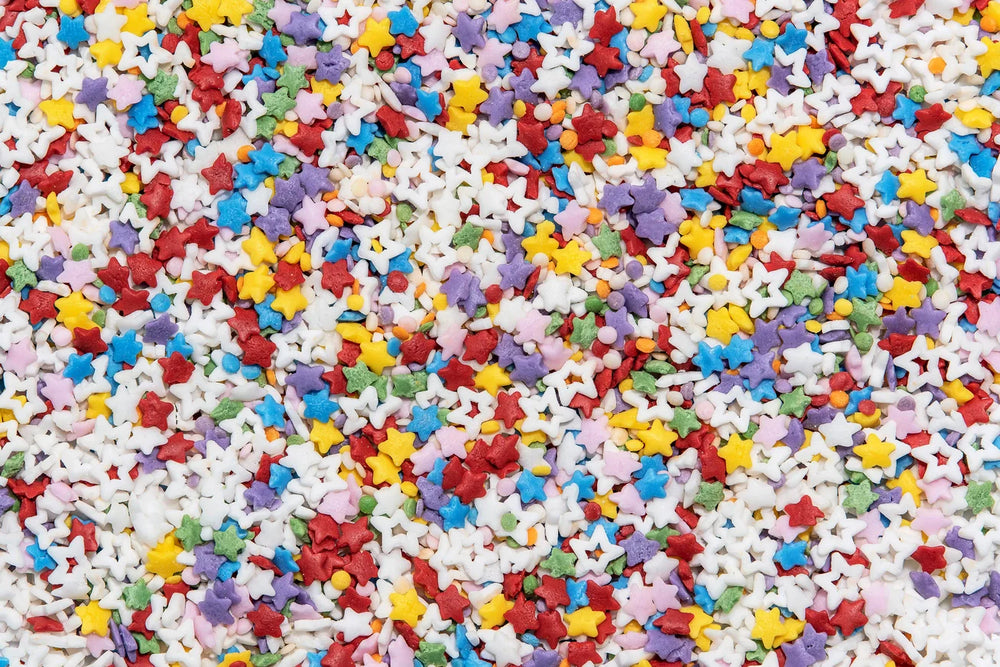 Colorful star-shaped sprinkles scattered on a white background