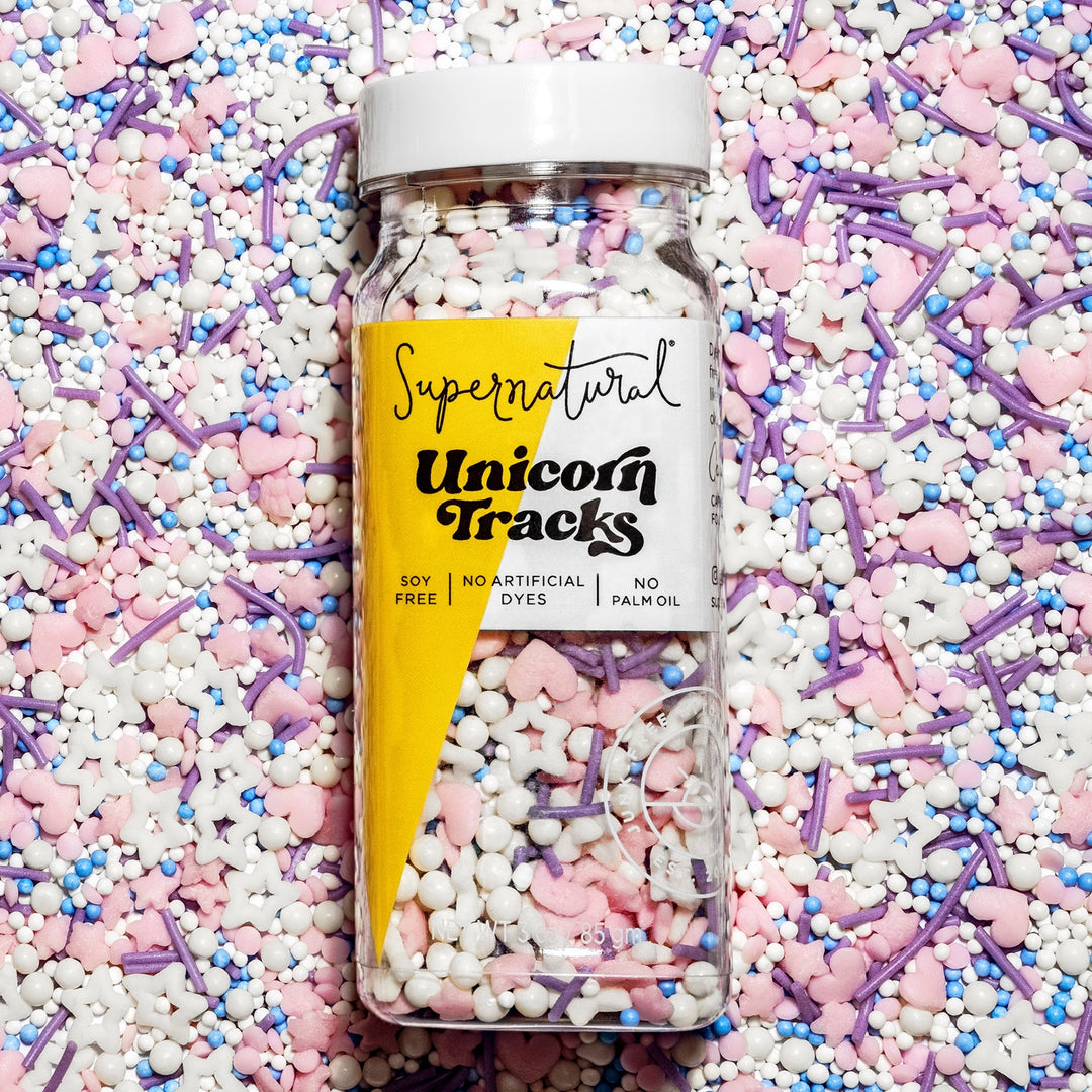 bottle of supernatural brand dye free sprinkle mix with heart and star shaped sprinkles in white, pink, blue, purple.