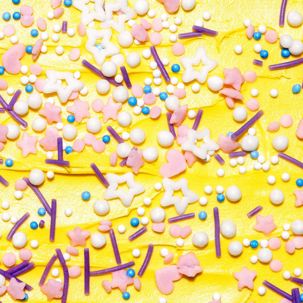 A close up picture of dye free unicorn themed baking sprinkles on yellow frosting