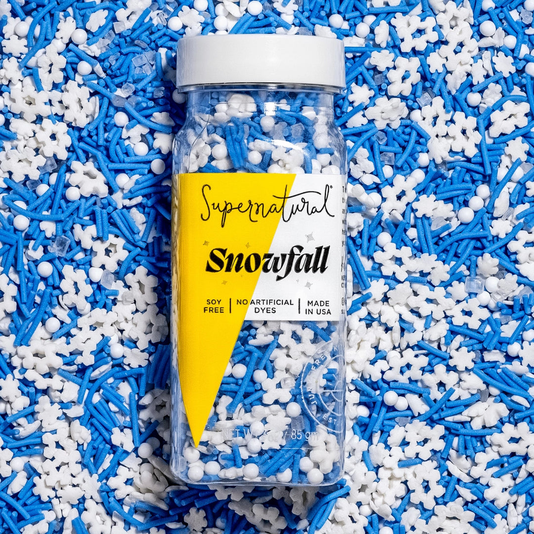 Bottle of 'Supernatural Snowfall' sprinkles on a bed of blue and white sprinkles.